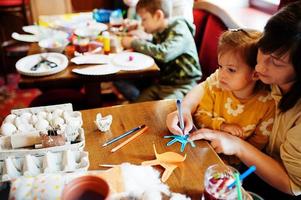 Vorbereitung auf das Osterkonzept. Kinder mit Mutter, die Häschen und Eier von Hand machen. foto