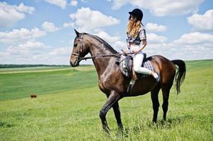 junges hübsches mädchen, das an einem sonnigen tag auf einem feld reitet. foto