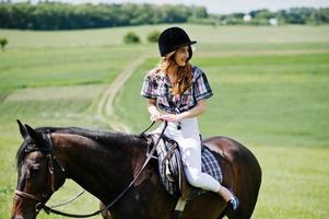 junges hübsches mädchen, das an einem sonnigen tag auf einem feld reitet. foto