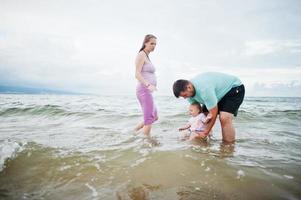 Sommerferien. eltern und menschen outdoor-aktivitäten mit kindern. schöne Familienferien. vater, schwangere mutter, kleine tochter am seesandstrand. foto