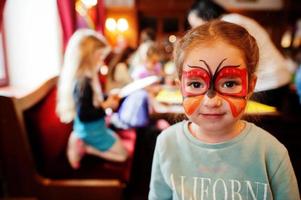 Vorbereitung auf das Osterkonzept. Babymädchen mit Schmetterlings-Aqua-Make-up im Gesicht. foto