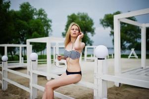 Porträt eines atemberaubenden jungen weiblichen Modells im Bikini, das neben dem weißen Holzzaun im Park posiert. foto