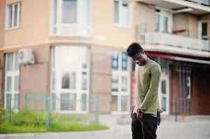 hübscher und attraktiver afroamerikanischer mann, der neben dem hohen gebäude auf einer straße posiert. foto