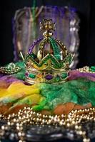 Königskuchen mit Krone, umgeben von Mardi Gras-Perlen, Nahaufnahme foto