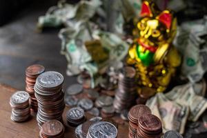 Stapel von Münzen, die den Blick auf die goldene Glückskatze und das Papiergeld im Hintergrund umrahmen foto