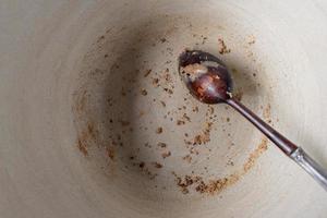 leere ländliche topfschüssel mit holzlöffel und übrig gebliebenen krümeln liegen flach foto