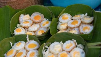 Gebratene Wachteleier in grünen Bananenblättern krathong. thailändisches streetfood, das gerne mit pfeffer und sojasoße gegessen wird foto