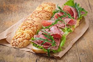 Sandwich mit Salami, Salat, Tomate und Rucola foto