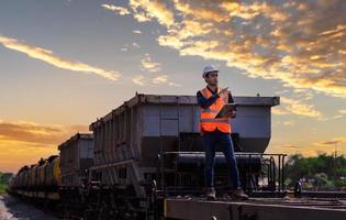 Ingenieur Eisenbahn unter Überprüfung des Bauprozesses Zugprüfung und Überprüfung der Eisenbahnarbeiten am Bahnhof mit Funkkommunikation. Ingenieur mit Sicherheitsuniform und Schutzhelm bei der Arbeit. foto