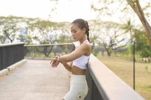 Eine junge Fitnessfrau in Sportbekleidung mit Smartwatch beim Training im Stadtpark, gesund und Lebensstil. foto