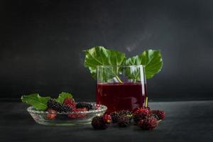 frische Maulbeerfrüchte in einer Schüssel und Saft in einem Glas foto