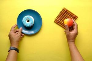 Hand hält Donuts und Apfel auf blauem Hintergrund foto
