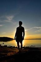 Schatten der Silhouette des Menschen im Sonnenuntergang in der Nähe des Sees foto