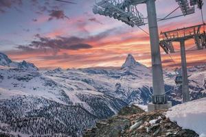 Seilbahnen, die bei Sonnenuntergang am Matterhorn gegen bewölkten Himmel fahren foto