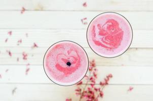 rosa Erdbeer-Smoothie auf hellbraunem rustikalem Tisch foto