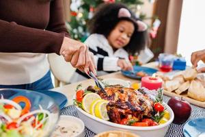 Glückliche Familie isst zu Hause zu Abend. feier und zusammengehörigkeit in der nähe des weihnachtsbaums. afroamerikanische Familie. foto