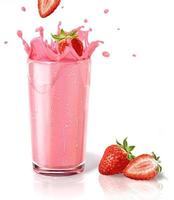 Erdbeeren spritzen in Milchshake-Glas, zwei andere auf dem Boden.
