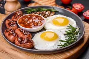 komplettes englisches frühstück mit bohnen, spiegeleiern, gebratenen würsten, tomaten und pilzen foto