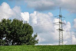 Sendeturm im grünen Feld gegen den bewölkten Himmel foto