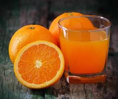 Orangensaftglas und frische Orangen auf Holz foto