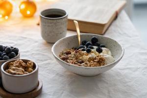 Buch lesen und gesundes Weihnachtsfeiertags-Winterfrühstück mit Müsli essen foto