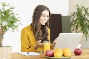 glückliche frau im headset, die per konferenz und video-chat auf dem laptop im büro spricht. Online-Bildung, Kurs foto