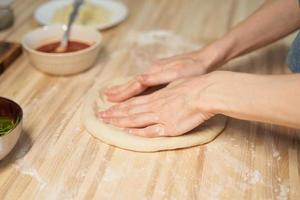 gesichtslose frau, die teig auf küchentisch zu hause, wohnung knetet. hausgemachtes Essen foto