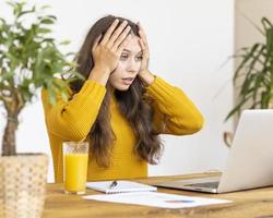 Mädchen überraschend, verärgert, Entsetzen im Gesicht. schöne junge Frau, die am Laptop arbeitet foto