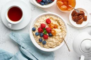 haferbrei mit blaubeeren, himbeeren, marmelade und nüssen, draufsicht. Frühstück mit Beeren foto