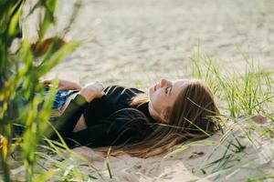 schöne Frau, die abends bei Sonnenuntergang am Strand liegt. hübsche Frau in Freizeitkleidung foto