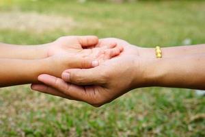 Die Hand der Mutter, die die Hand eines kleinen Mädchens auf Bokeh-Hintergrund hält. Liebes- und Familienkonzept. foto