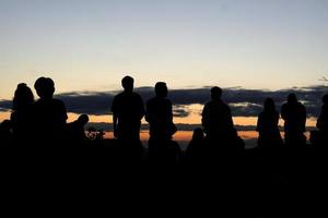 Silhouette von Touristen, die darauf warten, den Sonnenaufgang zu sehen foto