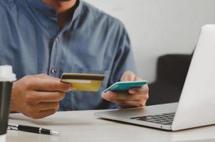 Geschäftsmann hält eine Kreditkarte und einen Taschenrechner an seinem Schreibtisch für Online-Einkäufe. foto