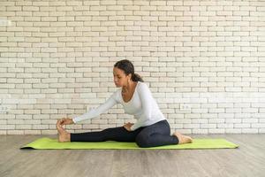 lateinische frau, die yoga auf matte praktiziert foto