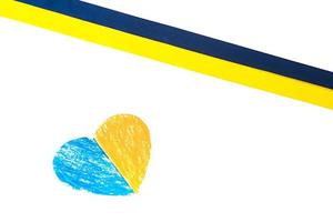 buntes blau-gelbes stoffband und papierherz, bemalt in der farbe der flagge der ukraine. isoliert auf weiß foto