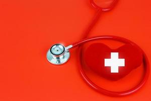 Weltrotkreuz und Rothalbmondtag - Blutspender - internationales Gesundheitskonzept - rotes Herz mit Stethoskop vor rotem Hintergrund foto