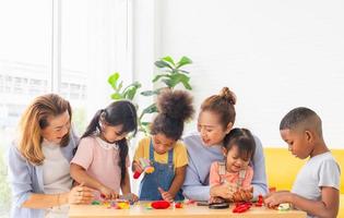 kinder spielen spielzeug und spiel zu hause mit positiven seniorengroßeltern im wohnzimmer, kleine mädchen und jungen verbringen glückliche zeit mit oma foto