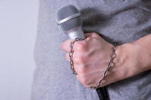 dynamisches Mikrofon Nahaufnahme auf dunklem Hintergrund, die Kette an seinem Arm. foto