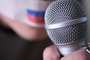 Ein mit Klebeband verklebter Mund mit einer russischen Flagge, der versucht, in ein Mikrofon zu sprechen. foto