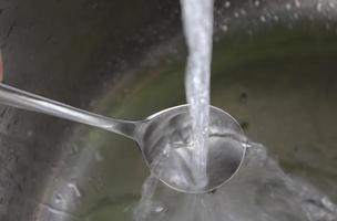 Fließendes Wasser aus einem Wasserhahn in den Abfluss eines verchromten Waschbeckens. foto