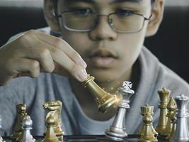 konzentrierter ernsthafter junge, der schachgambit, strategie entwickelt, brettspiel spielt, um clevere konzentration und denkendes kind beim schachspielen zu gewinnen. lern-, taktik- und analysekonzept. foto