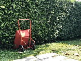 roter neuer Mauerzement-Wagenwagen, der im Garten mit Baumhintergrund parkt. Vintage-Stil. foto