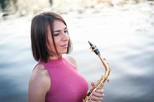 Frau spielt Saxophon bei Sonnenuntergang. foto