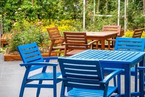 Holzblaue und braune Terrasse, Stuhl und Tisch im Garten mit farbenfrohem Blumenfeldhintergrund. foto