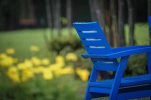 Halbblauer Stuhl im Garten mit verschwommener gelber Blume im Hintergrund. foto