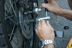 Nahaufnahme der Hand eines Technikers, festes Motorradrad an der Außenseite der Garage. foto