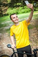 Ein junger Mann, der mit seinem Fahrrad ein Selfie macht. foto