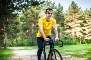 Porträt eines jungen Mannes, der sich auf einem Fahrrad fortbewegt. foto