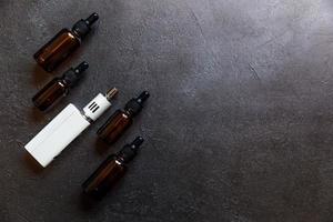 dampfgerät e-zigarette elektronische zigarette und flüssigkeitsflaschen auf dunkelschwarzem steinschieferhintergrund. Vape-Gerät für alternatives Rauchen. Vaping-Shop-Konzept. Gerät für Dampfer. Dampfzubehör. foto