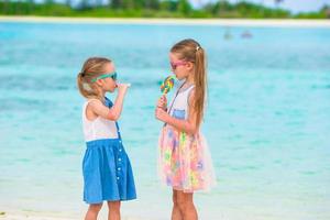 entzückende kleine Mädchen mit Lutscher am tropischen Strand foto